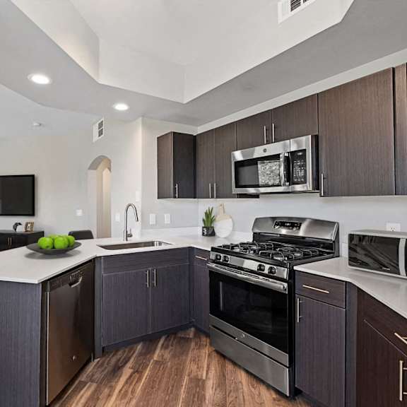 A modern kitchen with dark wood cabinets and stainless steel appliances.