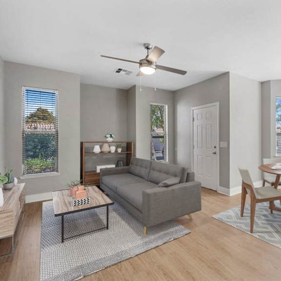 A living room with a grey couch, a coffee table, and a dining table with chairs.