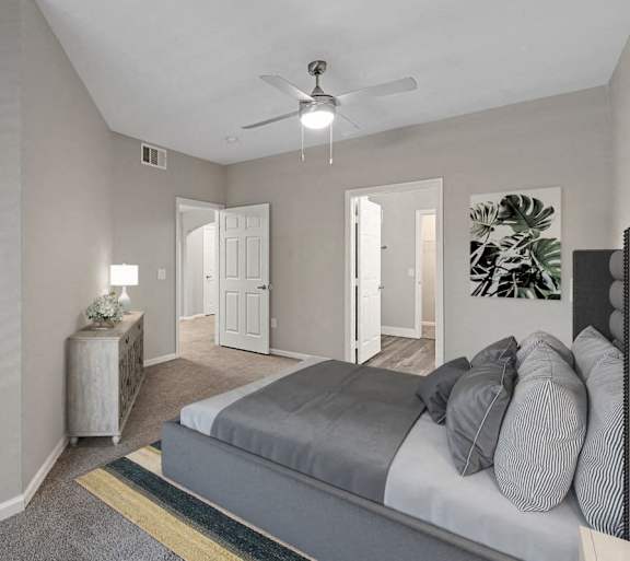 A bedroom with a bed, a ceiling fan, and a painting of a palm leaf on the wall.