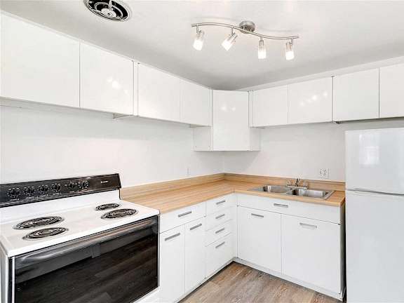 A white kitchen with a black stove top oven.