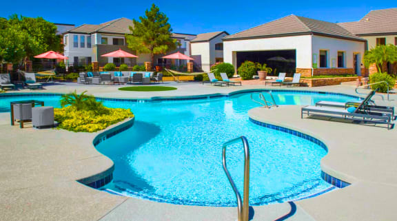 a swimming pool with lounge chairs and umbrellas in front of a building