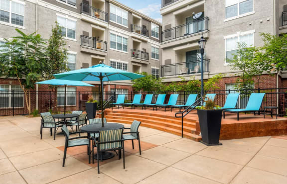 A patio with a table and chairs and a blue umbrella at Viridian in Greenwood Village, CO