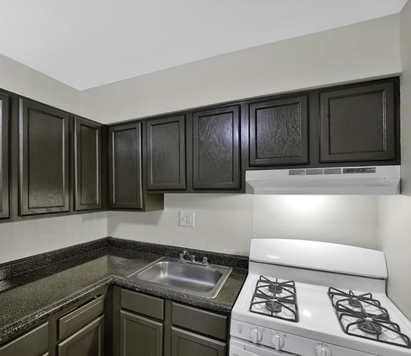 an empty kitchen with black cabinets and white appliances