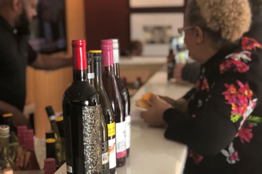 a woman sits at a counter with four bottles of wine