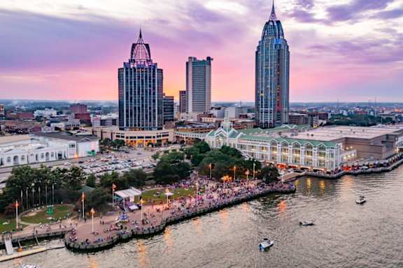 A cityscape with a river and boats, and a large building with a pointed top.