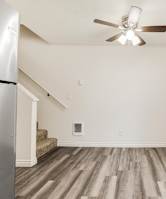 A room with a ceiling fan and wooden flooring.