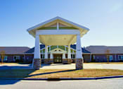 Thumbnail 1 of 8 - A building with a covered entrance and a stone pillar.