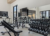 Thumbnail 20 of 52 - A gym with a variety of equipment including dumbbells and weight machines at Solhavn Apartments, American Fork, 84003