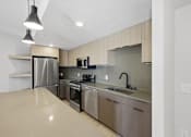 Thumbnail 18 of 51 - A modern kitchen with stainless steel appliances and a beige countertop at Brickside Heights, Millcreek, Utah