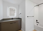 Thumbnail 38 of 51 - A modern bathroom with a white tub and a brown vanity at Brickside Heights, Millcreek, UT, 84106