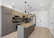 Thumbnail 11 of 51 - A modern kitchen with a large island in the middle at Brickside Heights, Millcreek, 84106