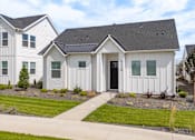 Thumbnail 6 of 20 - A white house with a black roof is surrounded by other similar houses. at Alante Homes at Spring Run, Idaho