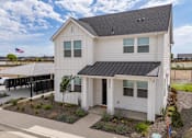 Thumbnail 5 of 20 - A white house with a black roof and a covered patio area at Alante Homes at Spring Run, Caldwell, ID, 83607.