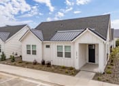 Thumbnail 8 of 20 - A white house with a black door and windows is surrounded by other similar houses. at Alante Homes at Spring Run, Caldwell, ID, 83607