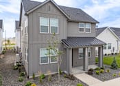 Thumbnail 1 of 20 - A grey house with a black roof and a gravel driveway. at Alante Homes at Spring Run, Caldwell, ID, 83607
