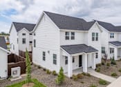 Thumbnail 7 of 20 - A white house with a black roof is surrounded by other similar houses. at Alante Homes at Spring Run, Caldwell, ID, 83607