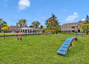 Thumbnail 3 of 5 - A playground with a blue seesaw and orange rings.