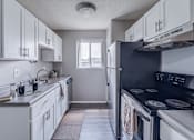 Thumbnail 3 of 6 - A kitchen with white cabinets and a black refrigerator.