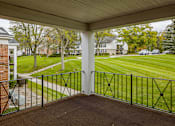 Thumbnail 3 of 5 - A view from a covered porch looking out at a grassy lawn and a row of houses.