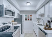 Thumbnail 2 of 5 - A modern kitchen with white cabinets and stainless steel appliances.