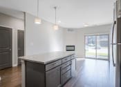 Thumbnail 4 of 8 - a kitchen with an island next to an open living room and a doorway to the hall