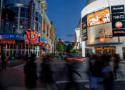 Thumbnail 8 of 9 - people crossing the street in front of a movie theater at night