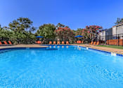 Thumbnail 1 of 42 - a large swimming pool with chairs and umbrellas in front of a building