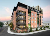 Thumbnail 1 of 31 - Exterior view of a modern apartment building with balconies, large windows, and street-facing landscaping.