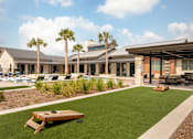 Thumbnail 6 of 25 - Upscale outdoor amenity area with a resort-style pool, covered lounge pavilion, and lawn games for residents to enjoy.