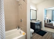 Thumbnail 19 of 25 - Modern bathroom featuring a spacious vanity, granite-style countertops, and a sleek tub-shower combination.
