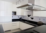 Thumbnail 1 of 5 - a white kitchen with black counter tops and white cabinets