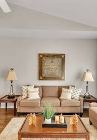 A living room with a couch, two chairs, a coffee table, and a painting on the wall.