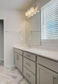 A bathroom with a walk-in shower, sink, and vanity.