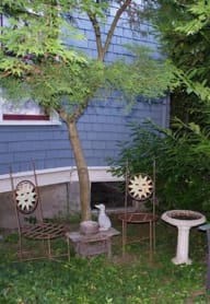 a garden with a bench and a table and chairs