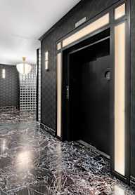 A hallway with a marble floor and a black door.