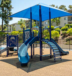 A playground with a blue slide and a blue umbrella.