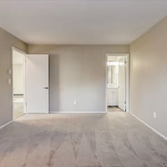 a bedroom with a carpeted floor and a door to a bathroom