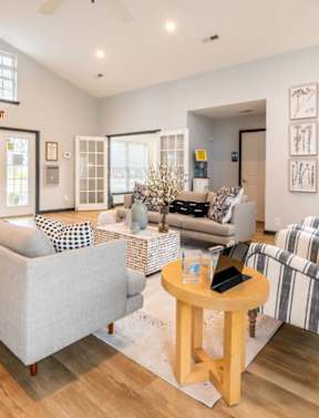 A spacious living room with a large rug and multiple seating options.