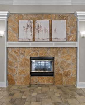 A stone fireplace with a fire going in it.