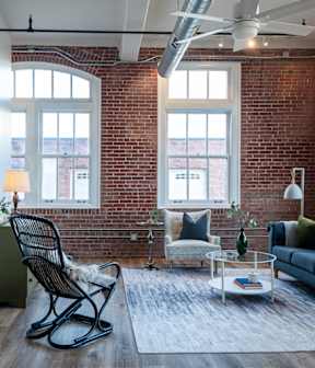 A living room with a black rocking chair and a grey sofa.