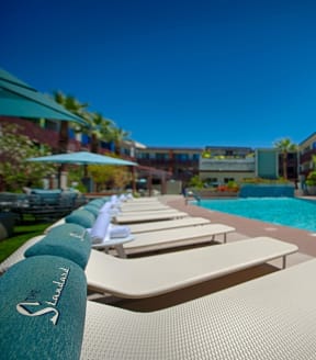 a pool with lounge chairs and umbrellas in front of a hotel