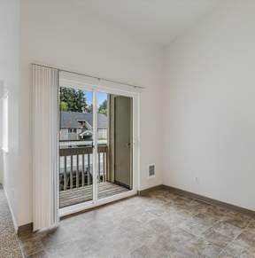 A room with a sliding glass door leading to a balcony.
