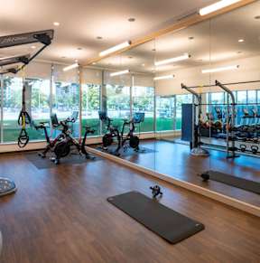 a gym with weights and other exercise equipment and a view of a tennis court