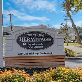 A sign for Hermitage Apartments stands in front of a building.