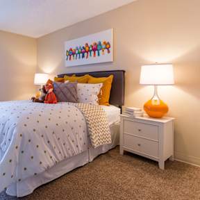 A bedroom with a bed, nightstand, and lamp.