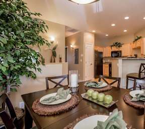 A dining table set with green apples and candles at Sereno Townhomes, Arizona, 85302.