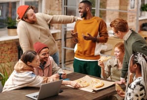 a group of people gathered around a table eating pizza