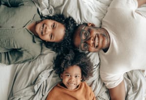 a couple and their child laying on a bed