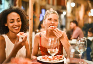 two women eating pizza at a table in a restaurant