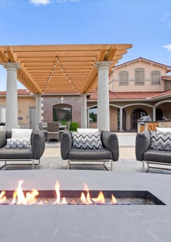 a fire pit in the middle of a patio with chairs around it
